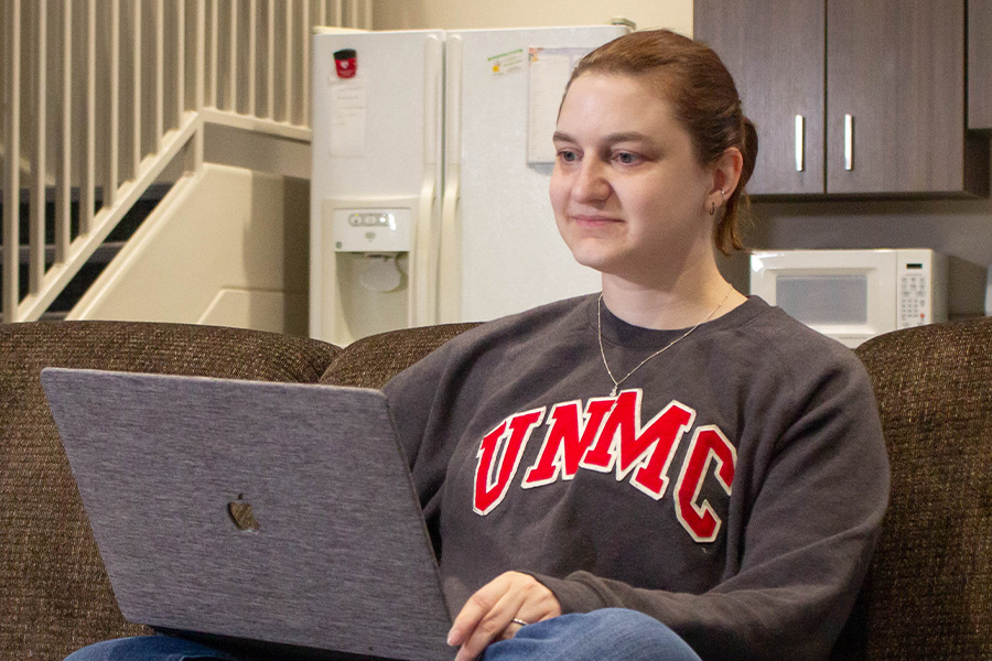 Student sits on couch with computer in lap