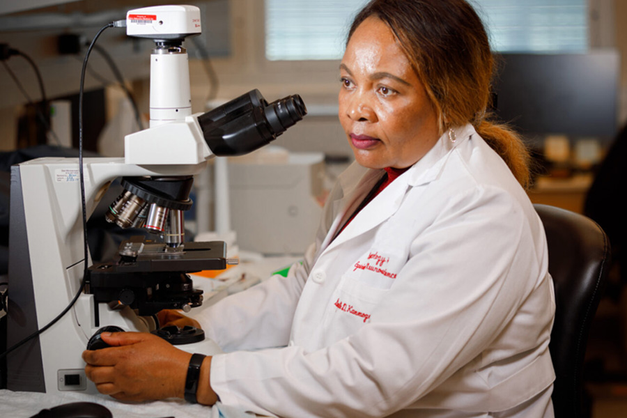 Georgette Kanmogne, PhD, in lab working with microscope.