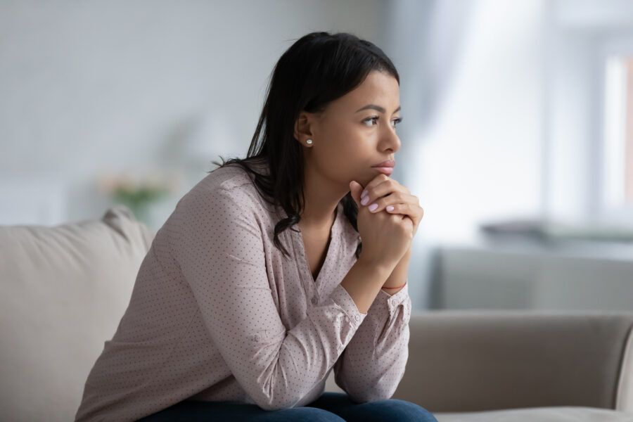 young woman sitting contemplatively, looking worried