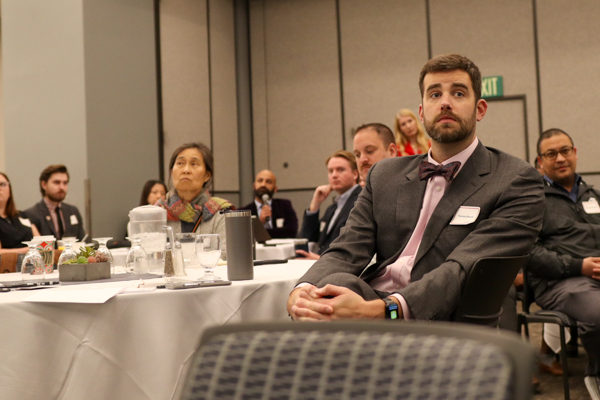 man sitting at table with other people listening to talks