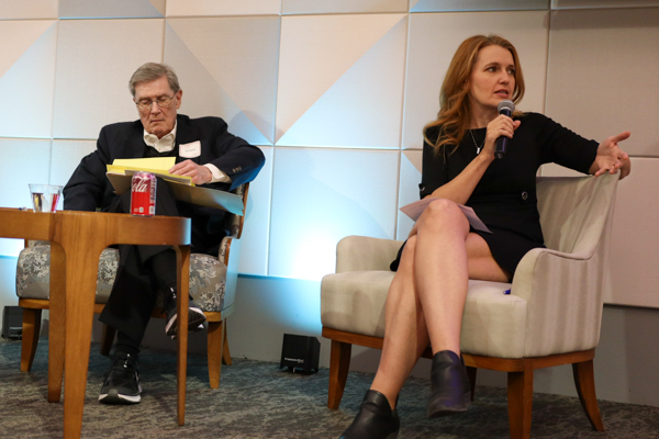 A woman and man sitting on stage talking at event