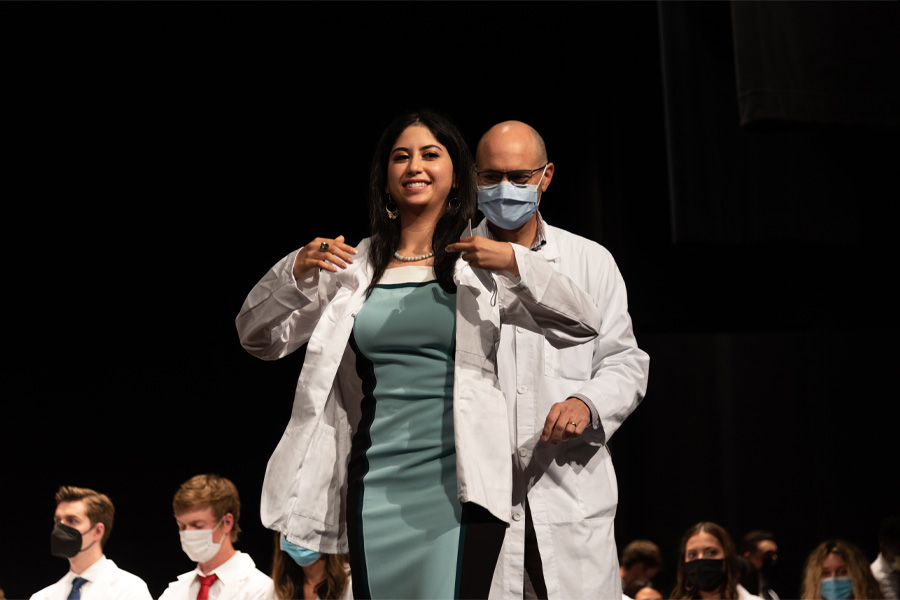 A medical student puts on a white coat on a stage