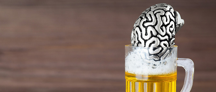 Silver brain model sitting in a mug of beer on a table, credit iStock.