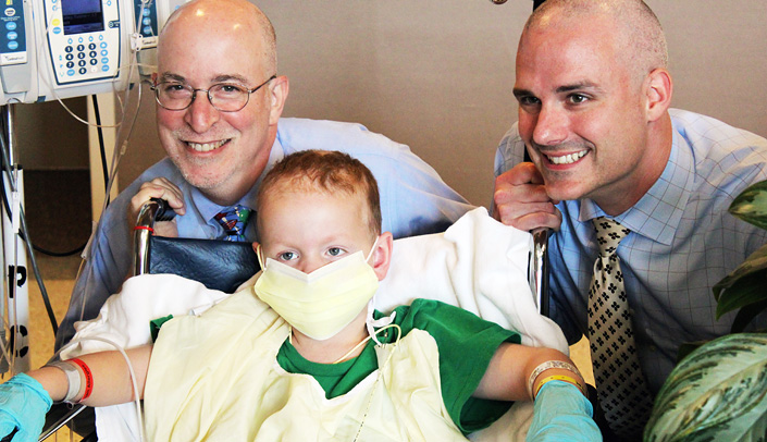 Bruce Gordon, M.D. (left) and Don Coulter, M.D., both pediatric oncologists/hematologists, are all smiles with their newly-shaven heads alongside 5-year-old Matthew Dinslage, who received a bone marrow transplant on July 4.