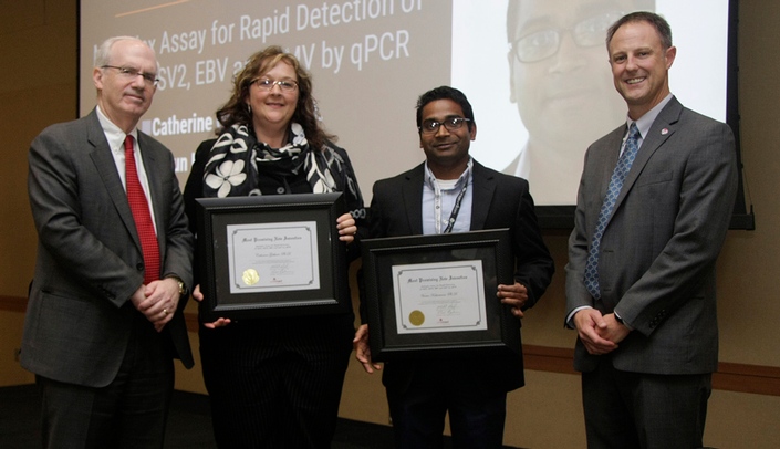 Two collaborators in the UNMC Department of Pathology and Microbiology -- Catherine Gebhart, Ph.D., second from left, and Varun Kesharwani, Ph.D., third from left -- took home the Most Promising New Invention Award. Joining them is UNMC Chancellor Jeffrey P. Gold, M.D., left, and UNeMed president and CEO Michael Dixon, Ph.D., right.