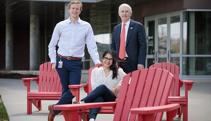 From left, UNMC Student Senate President Taylor Kratochvil, vice president Hannah Tandon and UNMC Chancellor Jeffrey P. Gold, MD, show off the new Adirondack chairs for the green space near the Ruth and Bill Scott Student Plaza.