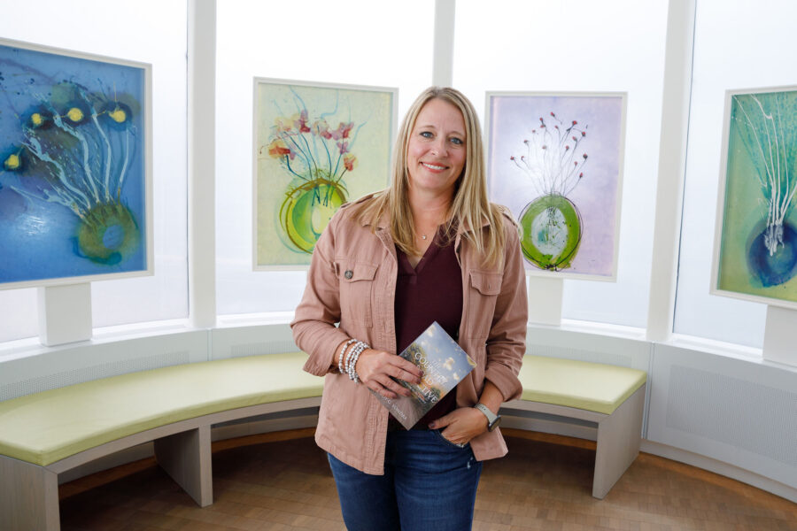 Jody Vondra&comma; in the Chihuly Sanctuary at the Fred & Pamela Buffett Cancer Center&comma; with a copy of her new book&comma; &OpenCurlyDoubleQuote;The Country Road Perspective"