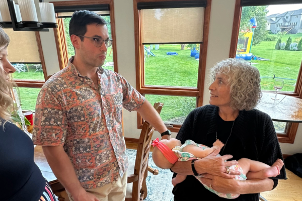 Male member of the department talks to female member of the department holding a baby