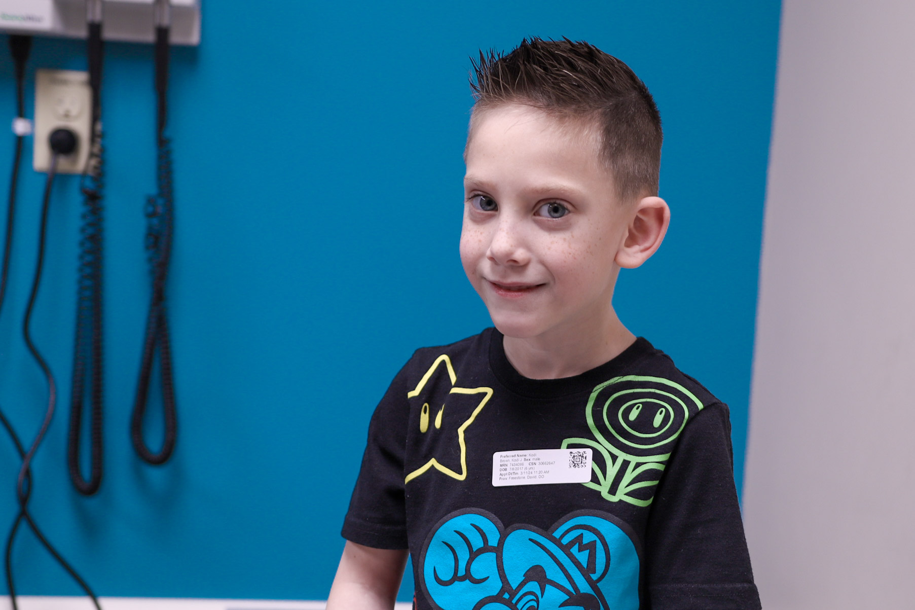 child looks at camera while doctor in the background looks at hand in cast