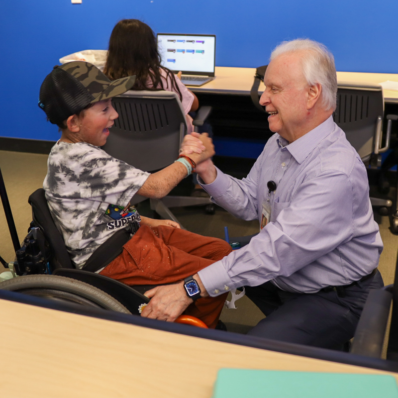 Doctor and child in wheel chair smile and shake hands