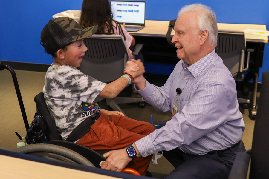 Doctor and young patient in wheel chair smiling and shaking hands