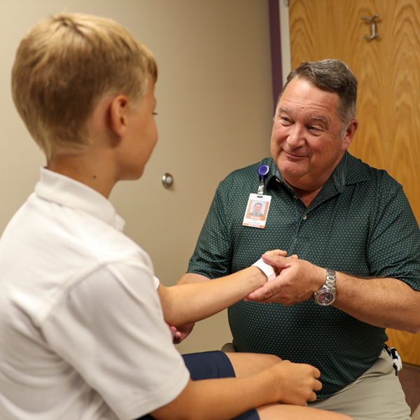 Dr. Kody Moffat examining arm of patient.