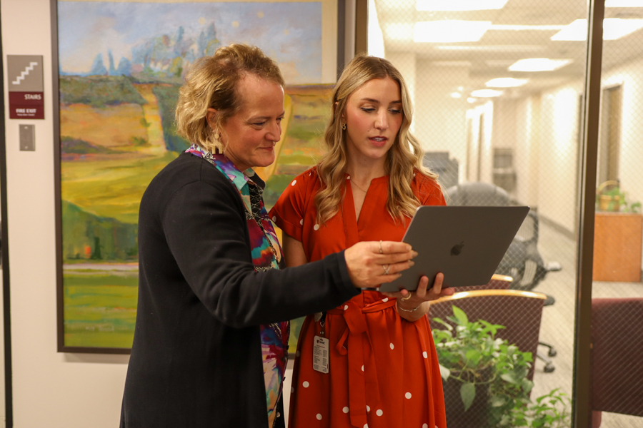 two women standing looking at laptop computer