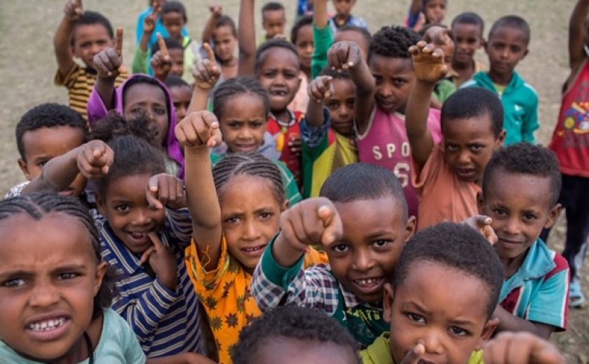 Kids raising their arms to the camera in Ethiopia.