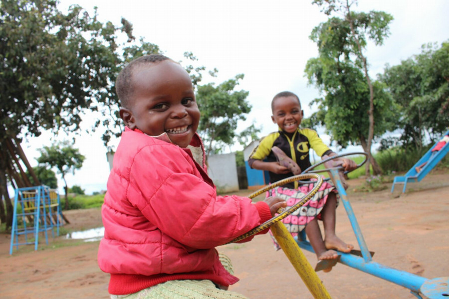 Children in Malawi smiling and playing at a playground