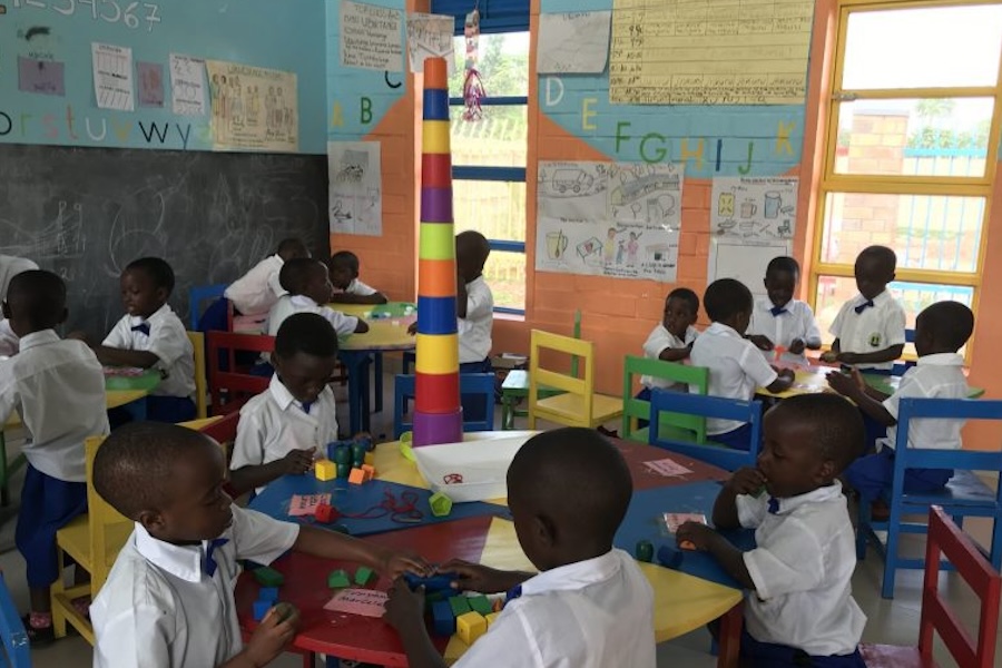 Young Rwandan students sitting at desks building with blocks