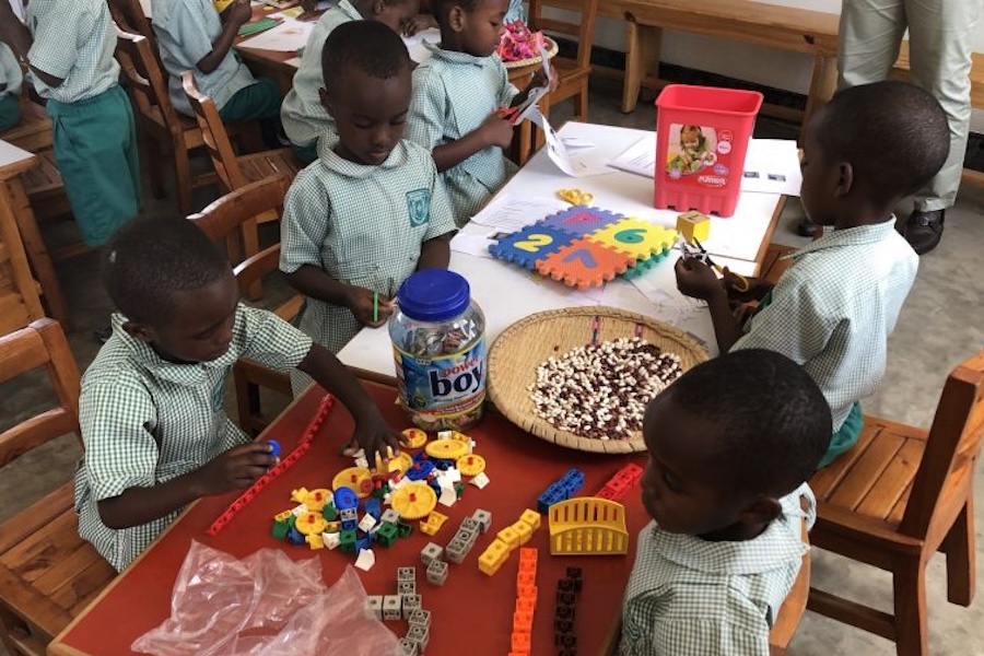 Young Rwandan students sitting at desks building with blocks