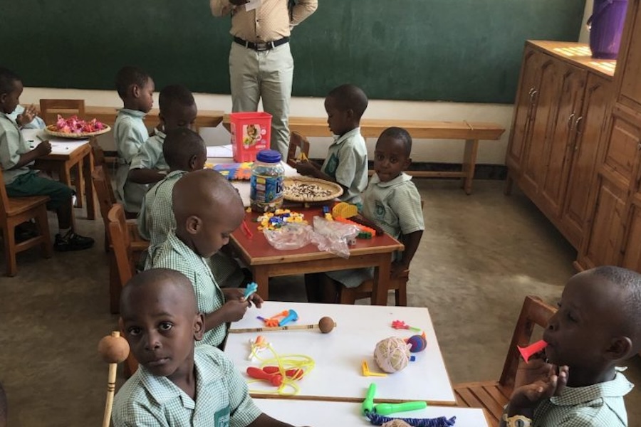 Young Rwandan children sitting at desks doing arts and crafts