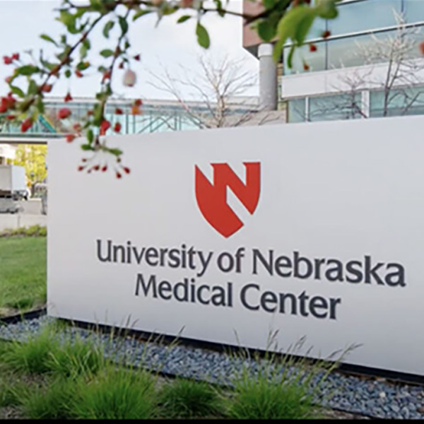 A person walks underneath a skywalk with a UNMC banner in the window