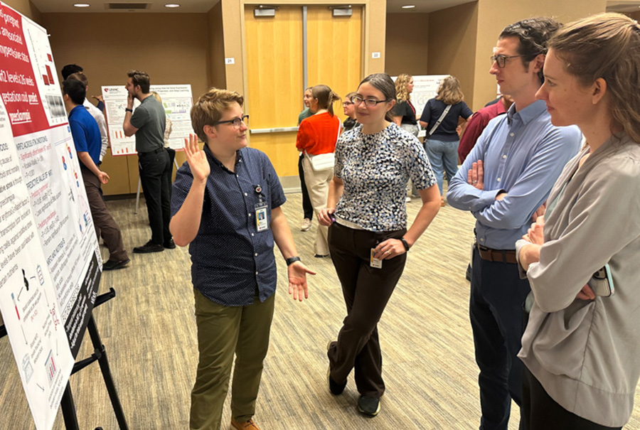 A student stands in front of a poster presentation of her research